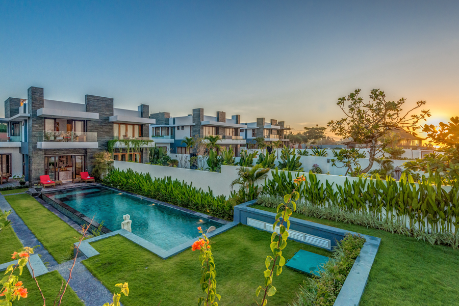 Beachfront villa cluster with a lap pool and landscaped gardens at dusk