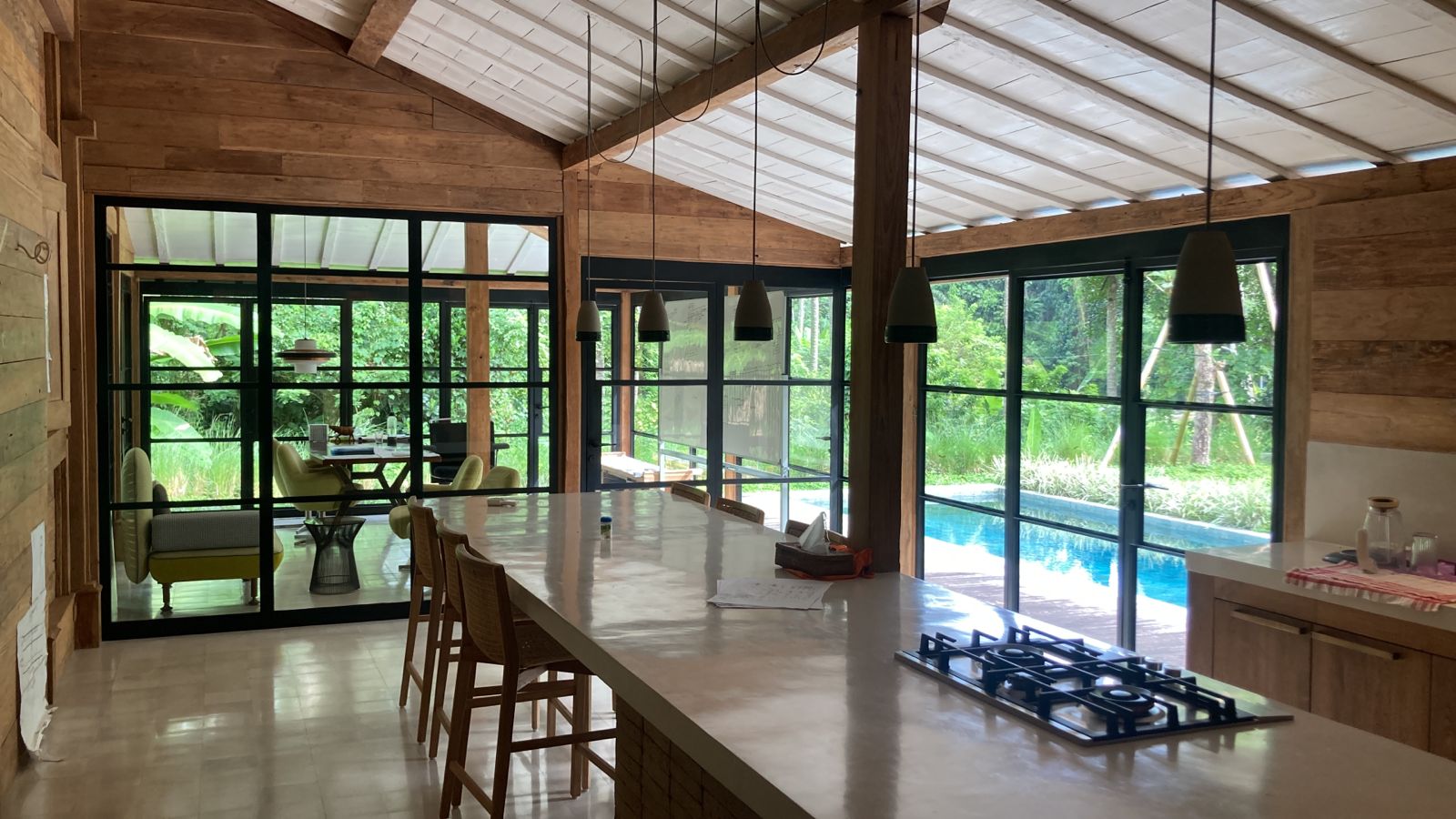 Ubud 3 — kitchen island under pendant lights with the pool beyond