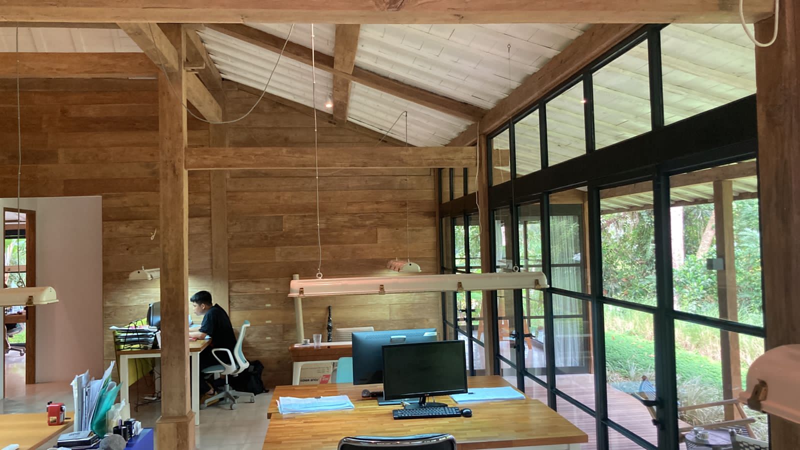 Ubud 3 — open workspace under the exposed timber roof and steel glazing